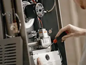 Furnace repair technician inspecting internal components and wiring in Orlando, FL