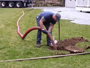 Septic pumping technician servicing a residential septic tank with a vacuum hose in Orlando, FL