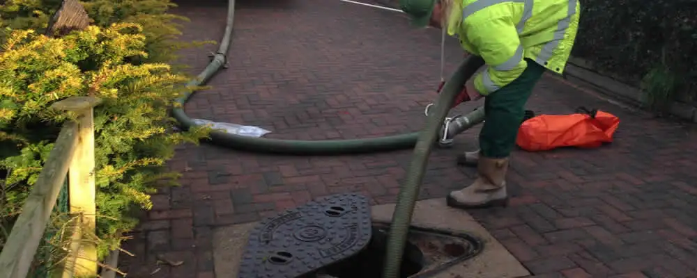 Septic tank cleaning technician servicing a septic tank with a vacuum hose in Orlando, FL