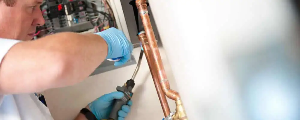 Water heater repair technician testing copper pipe connections and controls in Orlando, FL